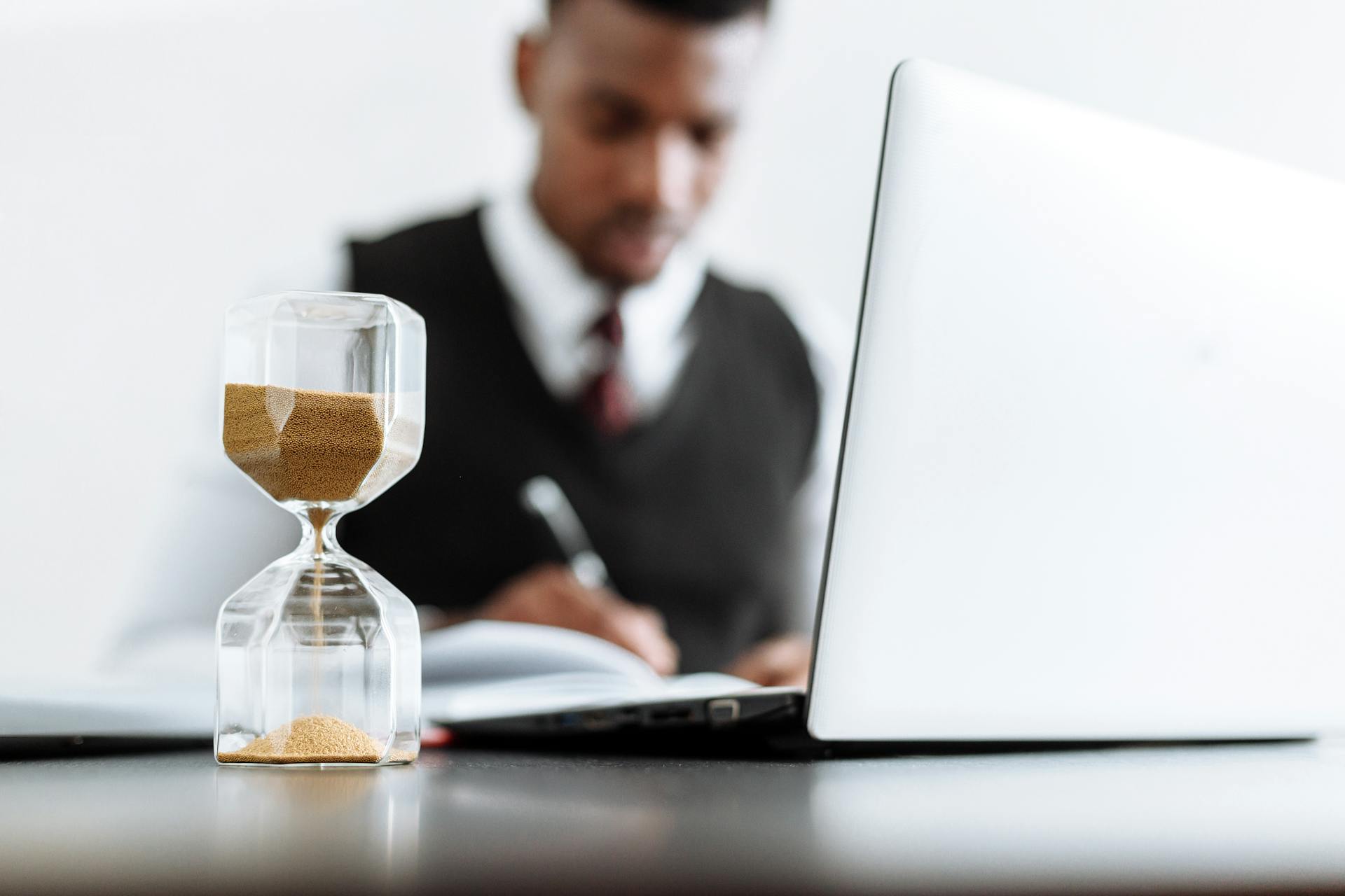 Hourglass and man in the background working at a desk